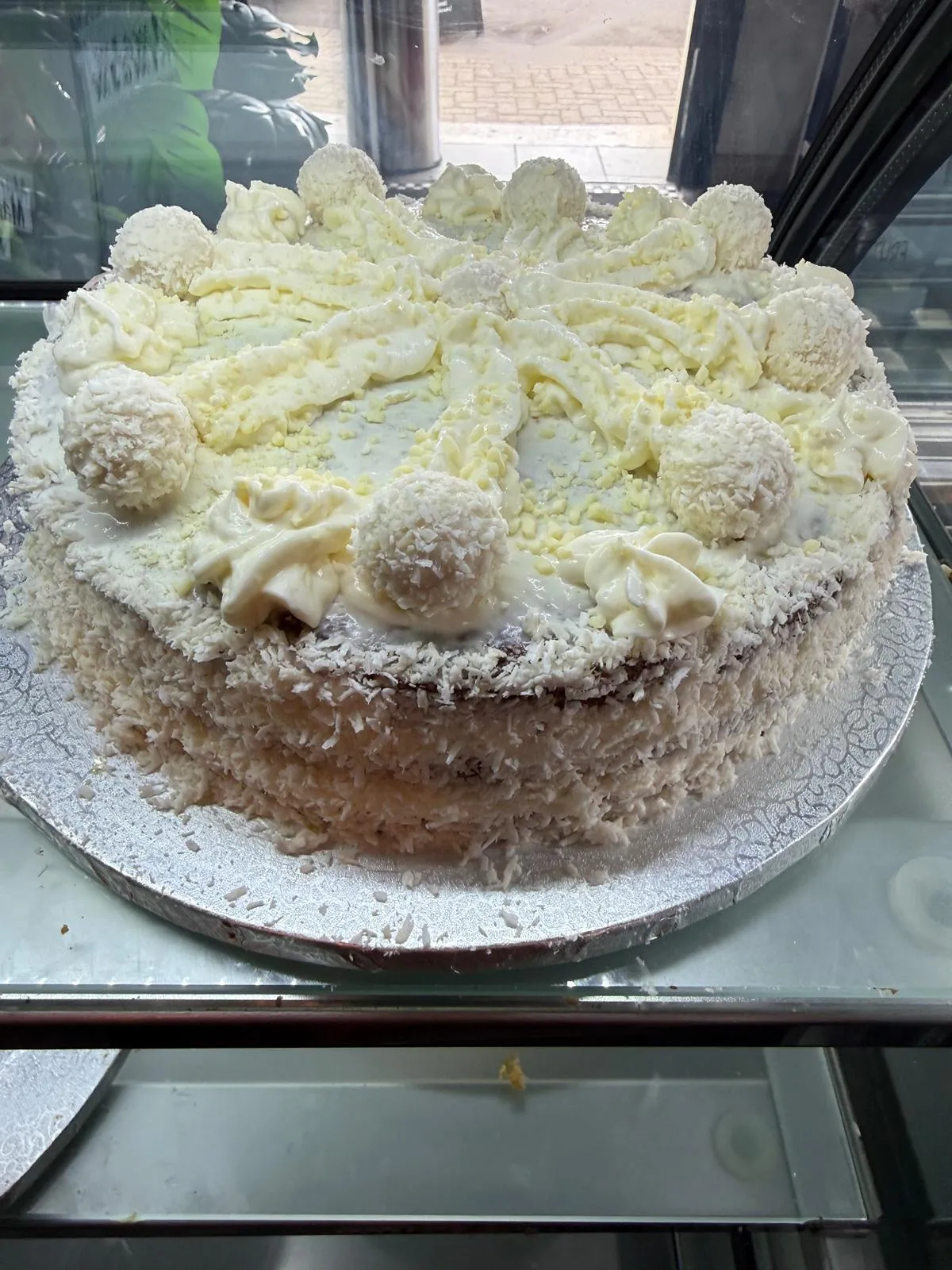 Ganze Kokos-Torte mit weißer Schokolade und Trüffeln in der Kühlvitrine