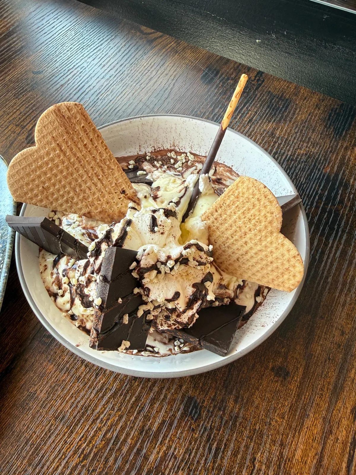 Schoko-Eisbecher mit Schokoladenstücken, Sahne und zwei Herzwaffeln