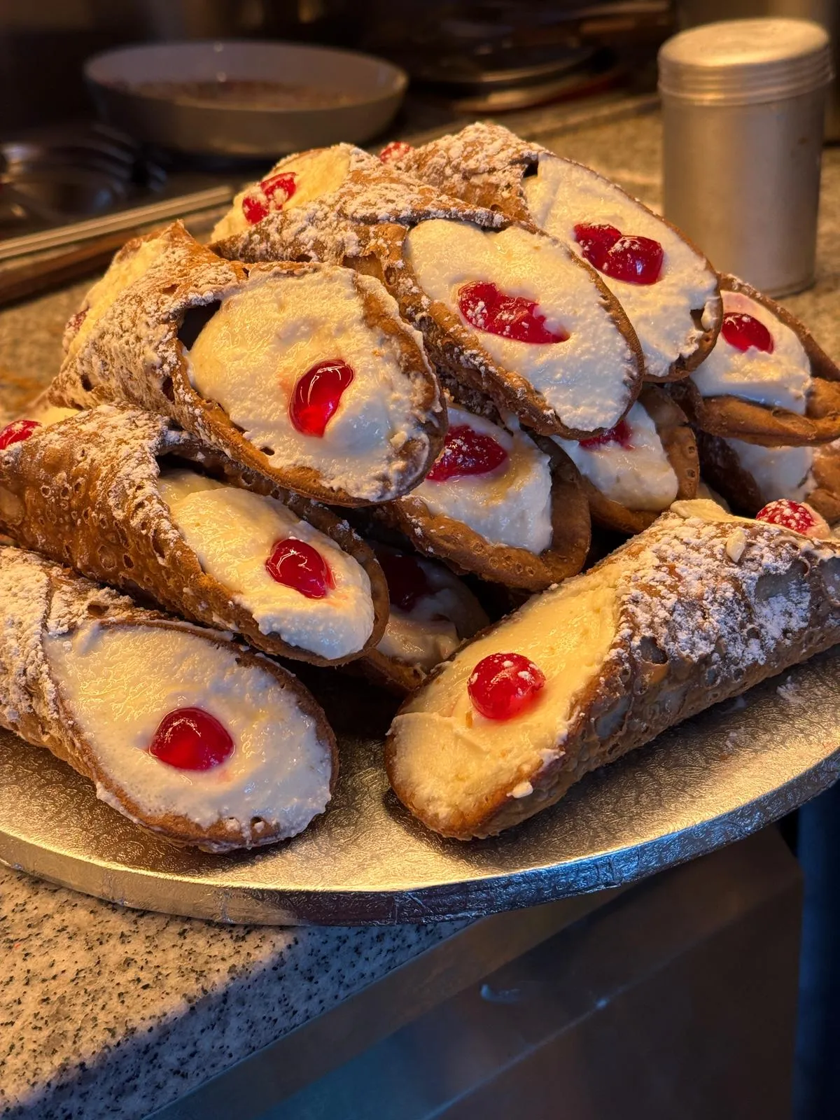 Großer Berg frischer, cremegefüllter Cannoli mit Kirschgarnitur und Puderzucker