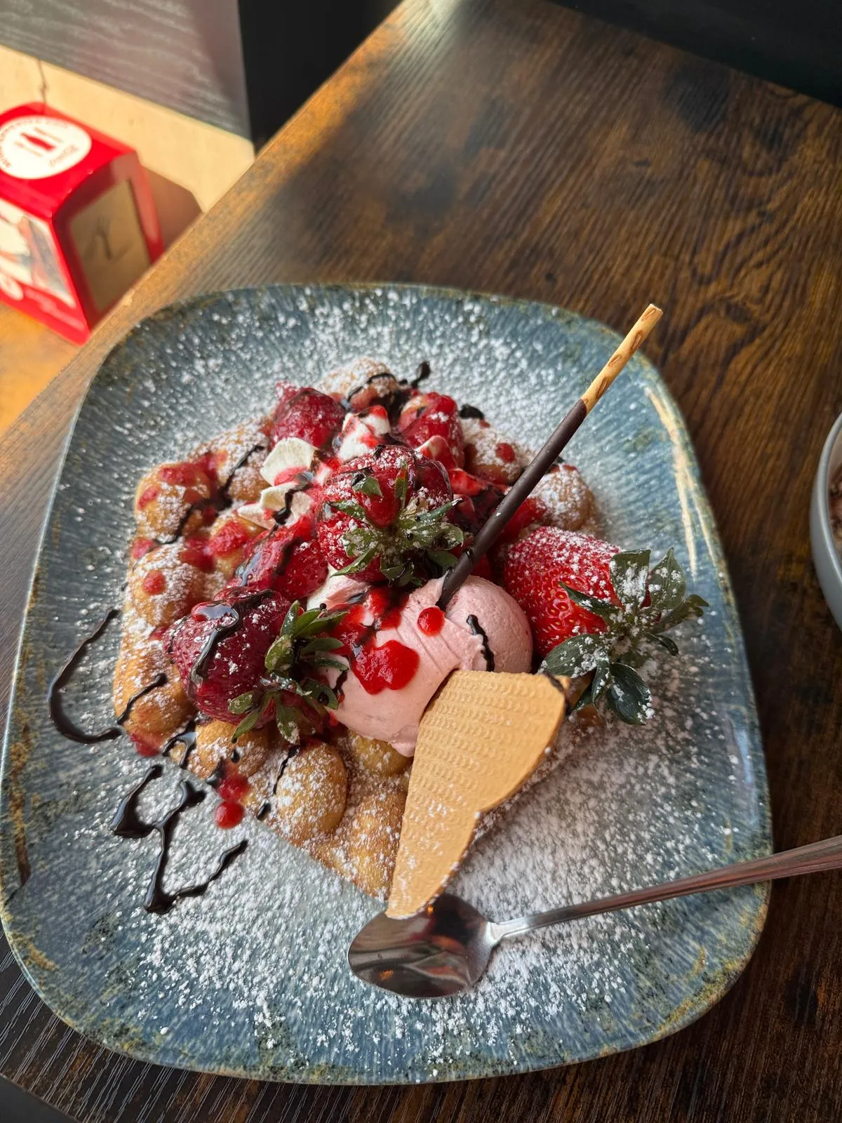 Bubble Waffel mit frischen Erdbeeren, Erdbeereis und Herzwaffel auf blauem Teller